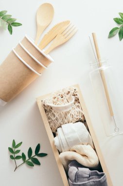 Sıfır atık. Çevre dostu bambu sofra takımı ve beyaz arka planda yeşil yapraklı kumaş eko torbaları..