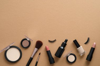 Profesyonel makyaj aletleri. Kahverengi arka plandaki ürünleri uydur. Düz yatış, üst görünüm.