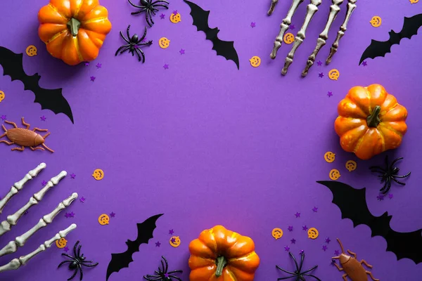 stock image Happy Halloween holiday concept. Halloween decorations, skeleton hands, bats, pumpkins on purple background. Halloween party greeting card mockup with copy space. Flat lay, top view, overhead.