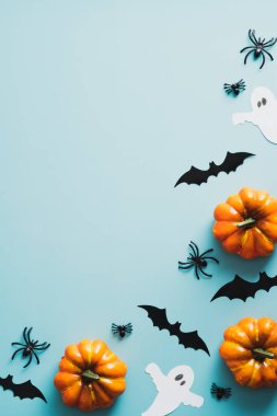 Cadılar bayramı konseptin kutlu olsun. Cadılar Bayramı süslemeleri, yarasalar, hayaletler, balkabakları, mavi arka planda örümcekler. Cadılar Bayramı partisi davetiyesi fotokopi alanı ile birlikte. Düz yatış, üst görünüm.