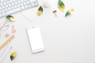 Zarif kadınsı çalışma alanı. Boş ekran maketli akıllı telefon, ofis malzemeleri, beyaz arka planda bilgisayar klavyesi. Düz konum, üst görünüm, kopyalama alanı.