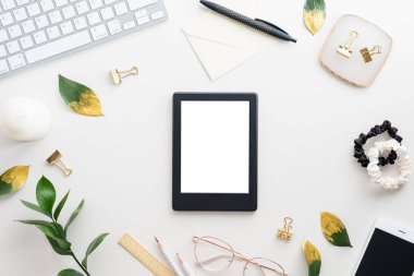 Boş ekranlı, klavyeli, beyaz arka planda altın yapraklı tablet kaplı kadınsı masa. Şık bir çalışma alanı. Düz yatış, üst görünüm.