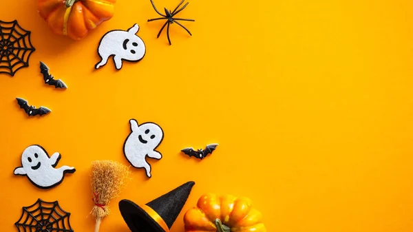 Happy Halloween holiday concept. Halloween decorations, pumpkins, bats, ghosts, bats on orange background. Halloween party greeting card mockup with copy space. Flat lay, top view, overhead.