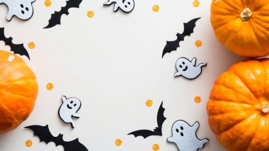 Mutlu Cadılar Bayramı konsepti. Kabaklardan, hayaletlerden, beyaz masadaki sopalardan yapılmış bir çerçeve. Düz yatış, üst görünüm.