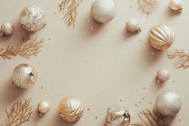 Altın topları ve bej arka planda Xmas ağaç dalları olan bir Noel çerçevesi. Düz konum, üst görünüm, kopyalama alanı.