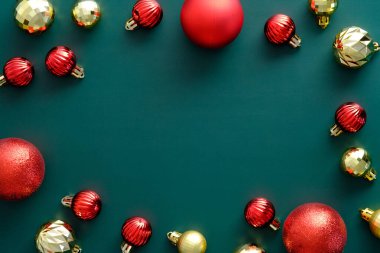 Yeşil arka planda kırmızı ve altın toplarla süslenmiş Noel çerçevesi. Düz yerde, üst tarafta. Noel afişi tasarımı, eski tarz.