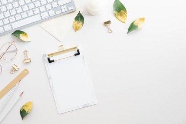 Kağıt pano, klavye, beyaz arka planda ofis aksesuarları olan ofis masası. Zarif kadınsı çalışma alanı. Düz yatıyordu, üstten, yukarıdan..