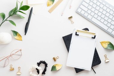 Üst kattaki ofis masasında yatıyordu. Beyaz zemin üzerinde pano, yeşil yapraklar ve klavye ile kadınsı masa çalışma alanı.