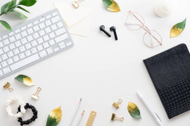 Kadın ofis masası dümdüz uzanıyordu. Klavyeli, defterli, gözlüklü, beyaz arka planda aksesuarlı bir kadın çalışma alanı. Üst görünüm kadınsı işyeri