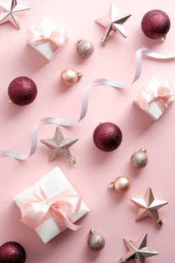 Noel kompozisyonu. Noel pembe süslemeleri ve pastel pembe arka planda hediye kutuları..