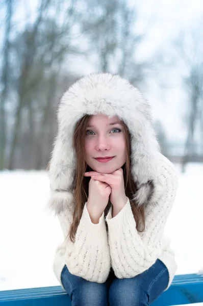 Portrait of a young beautiful girl in a cap with earflaps in a cool winter park — Stock Photo, Image