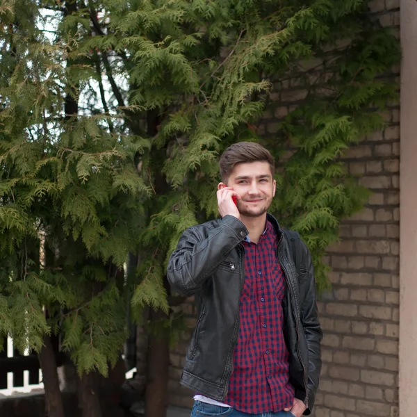 Schöner Hipster in Lederjacke telefoniert draußen — Stockfoto