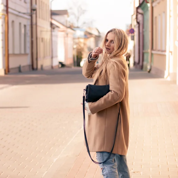 Amazing blonde girl walking alone on the road in old european city.