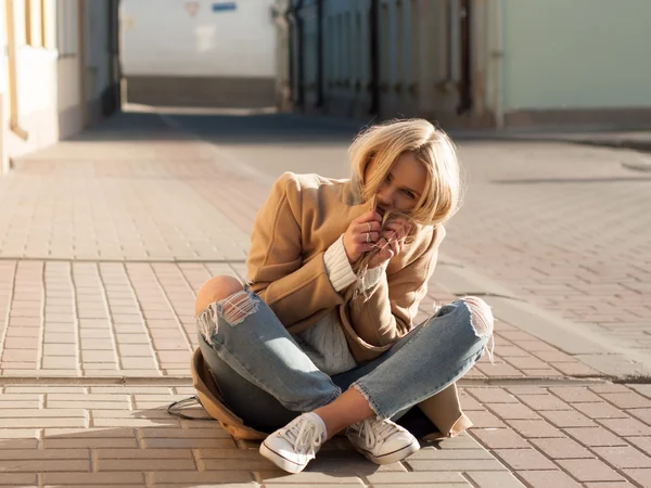 Joven mujer rubia bastante de moda vestida con jeans rasgados y suéter blanco — Foto de Stock