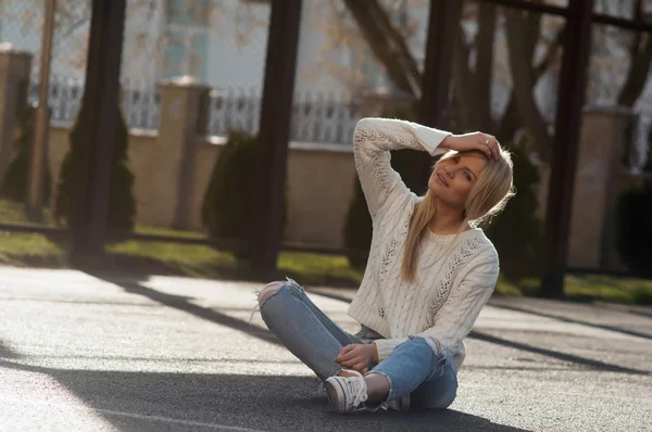 Joven mujer rubia bastante de moda vestida con jeans rasgados y suéter blanco — Foto de Stock