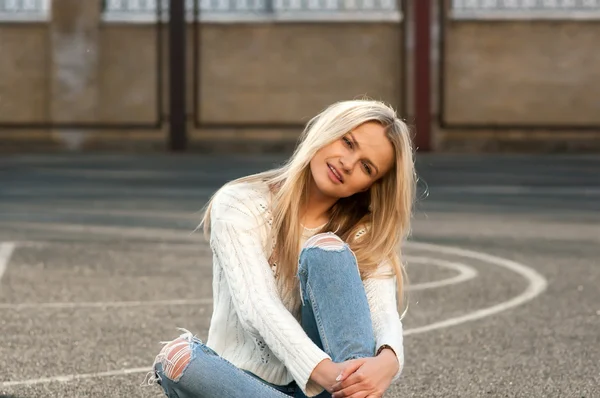 Jovem mulher loira bonita moda vestida de jeans rasgado e suéter branco — Fotografia de Stock