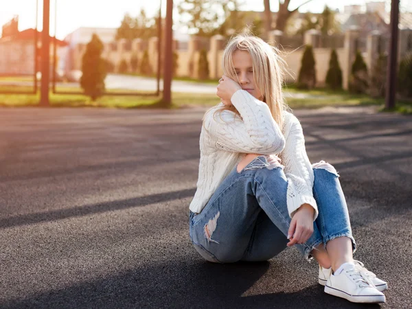 Jovem mulher loira bonita moda vestida de jeans rasgado e suéter branco — Fotografia de Stock