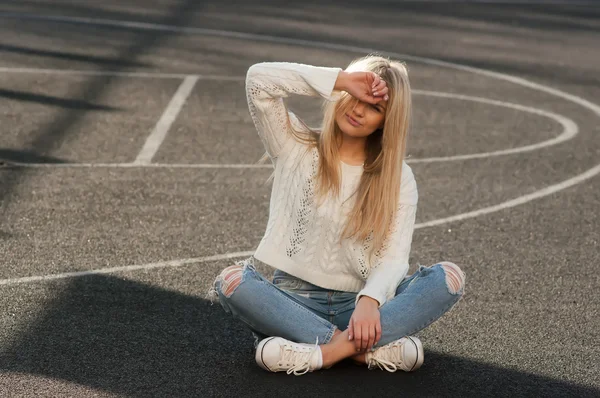 Jovem mulher loira bonita moda vestida de jeans rasgado e suéter branco — Fotografia de Stock