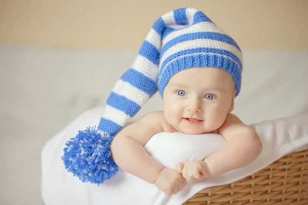 Sorridente bambina in blu cappello a maglia si trova al cesto Fotografia Stock