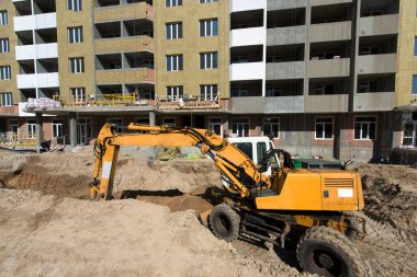 Kazıcı bir çukur kazıyor. İnşaat alanı. Dairelerin üretimi, sosyal konutlar.