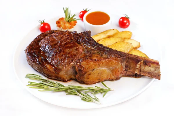 Gegrilltes Steak auf Knochen mit Kartoffeln lizenzfreie Stockbilder