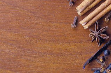 Noel baharatları, tarçın, yıldız anason, burbon vanilya, karanfil, ahşap ceviz dilimleme tahtasındaki ardıç meyveleri. Yiyecek, baharat ve Noel kavramları