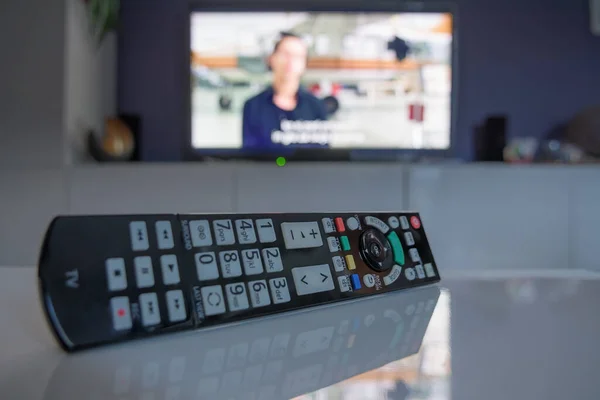 Akıllı televizyon setinin önündeki sehpanın üstündeki uzaktan kumandayı kapat. Televizyon, teknoloji, haber ve eğlence kavramları