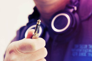Stereo kriko, TRS konnektörü, boynunda kulaklık olan bir adam tarafından tutuluyor. DJ, müzik, bağlantı kavramları