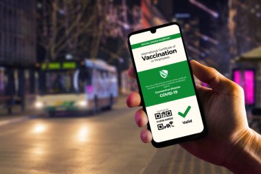 Dijital aşı pasaportu, COVID-19 için yeşil geçiş kartı, erkek elinde tutulan akıllı telefondan sergileniyor. Aşı, hastalık dokunulmazlığı pasaportu, sağlık ve gözetim kavramları