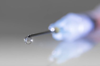 Close-up of droplet on the tip of a syringe needle. Healthcare, pharmaceutical industry, drug abuse and vaccination concepts clipart