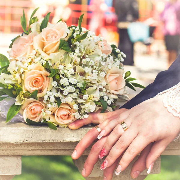 Hands and rings on wedding bouquet — Stock Photo, Image