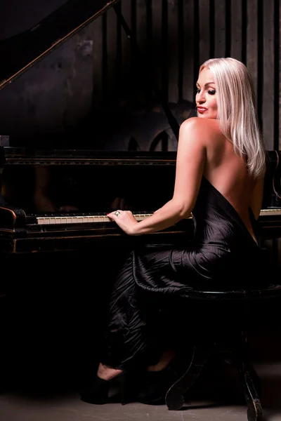 Bella ragazza seduta vicino al pianoforte — Foto Stock