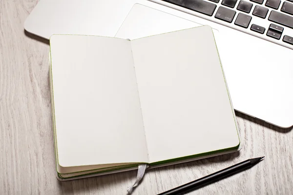 Open notepad with blank pages on white table with laptop — Stock Photo, Image