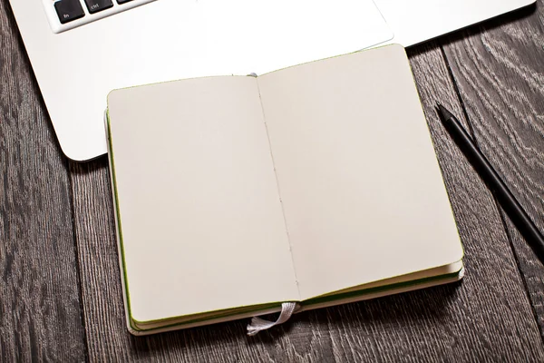 Ανοίξτε το σημειωματάριο με κενές σελίδες στο τραπέζι με laptop — Φωτογραφία Αρχείου