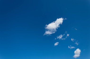 Parlak mavi gökyüzü, beyaz bulutlar, doğal bir arkaplana saçılmış.