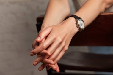 Kadın, ellerini bir sandalyenin arkasına yasladı. İki çıplak kadın eli birbirine bağlandı. Yakın durun.