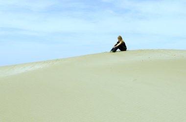 girl sitting on top of a dune clipart
