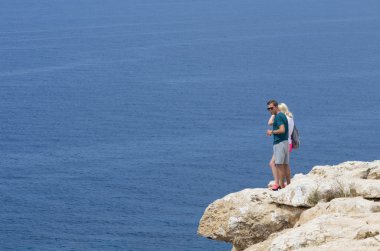 İki insan deniz tarafından kayalık uçurum izliyor