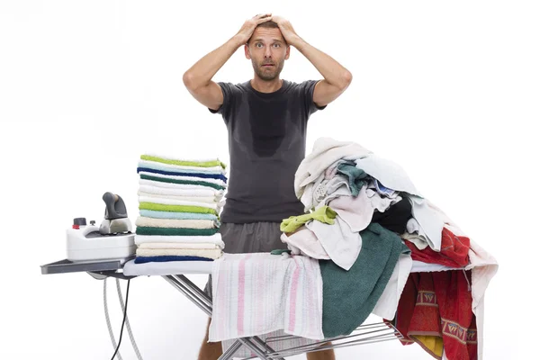 Desperate man with hands in his hair behind an ironing board — Stock Photo, Image