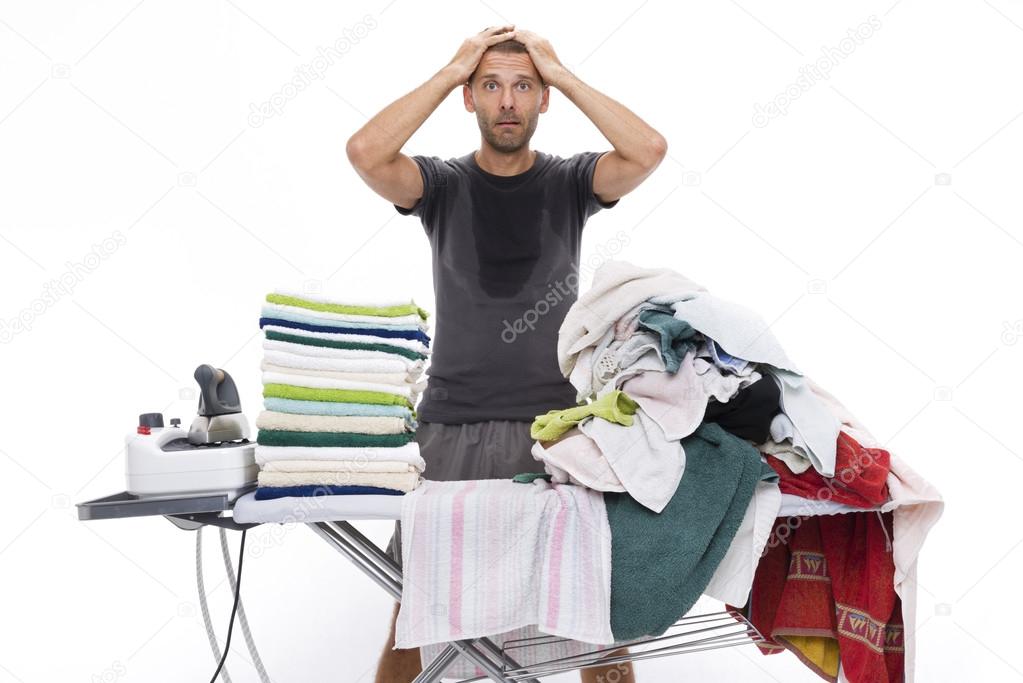 Desperate man with hands in his hair behind an ironing board