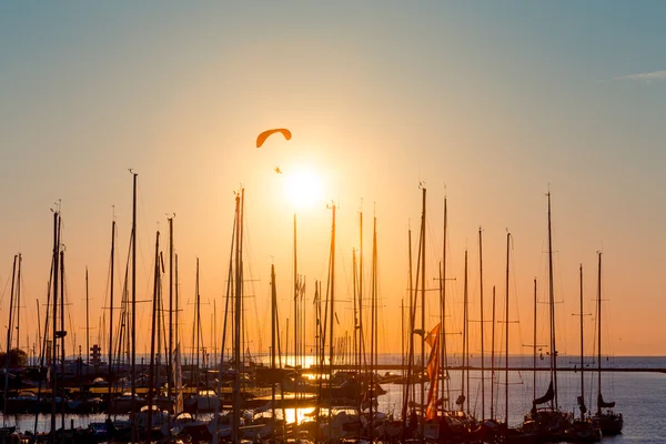 Sunset paragliding over yachts — Stock Photo, Image