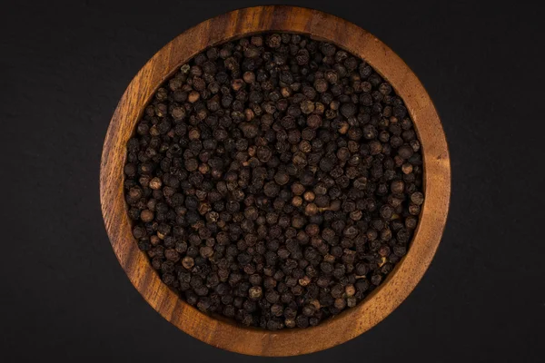 Черный перец в деревянной чаше — стоковое фото