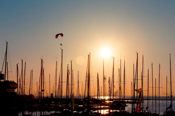 Sunset paragliding over yachts — Stock Photo, Image