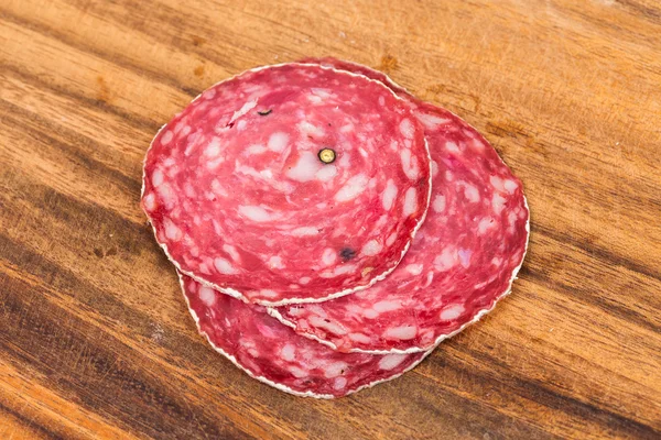 Plakje salami op houten bord — Stockfoto