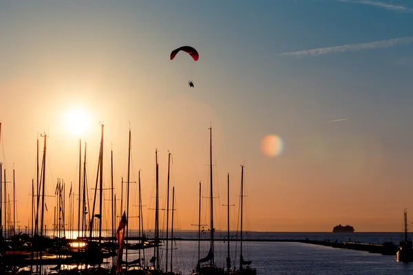 Sunset paragliding over yachts — Stock Photo, Image