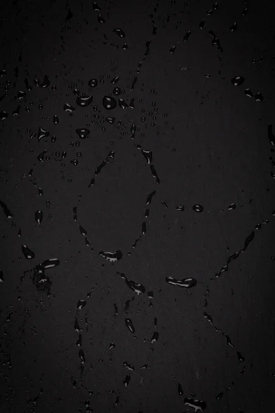 Krople wody na ciemnej powierzchni kamienia — Zdjęcie stockowe