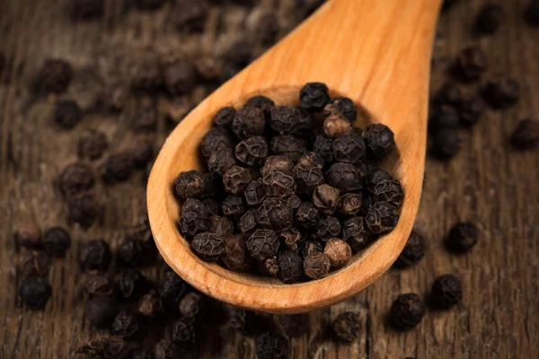 Pimienta negra sobre cuchara de madera — Foto de Stock