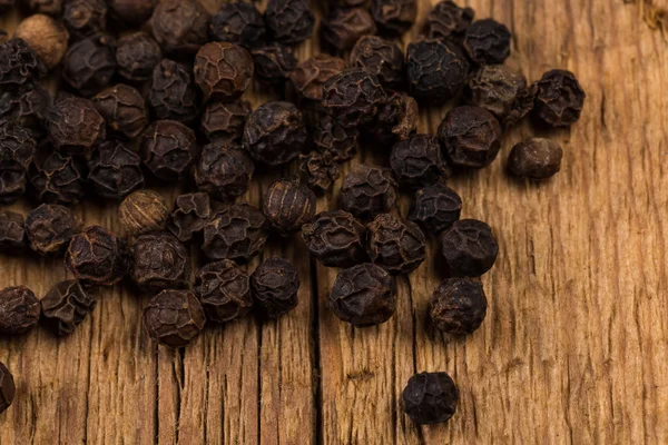 Black pepper on wooden table — Stock Photo, Image