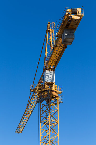 Yellow tower crane in the blue sky