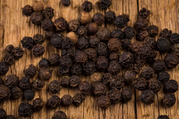 Pimenta preta na mesa de madeira — Fotografia de Stock